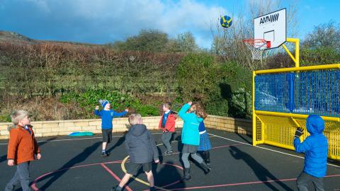 Some boys and girls play basketball during playtime