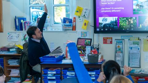 The teacher reads to his class from an interactive whiteboard