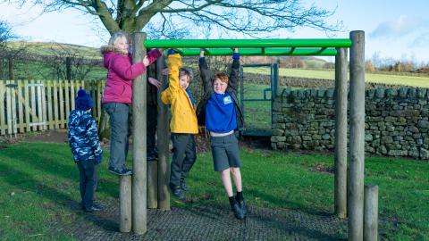 Some boys and girls swing on the monkey bars