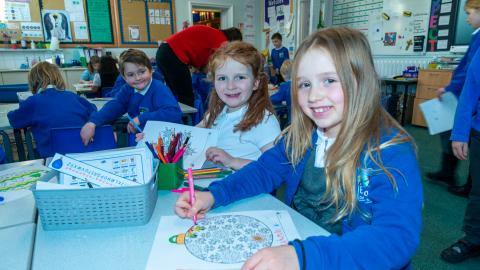Children in a classroom setting colouring in pictures